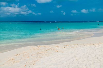 People swimming in sea against sky