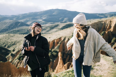 Friends standing on mountain against sky