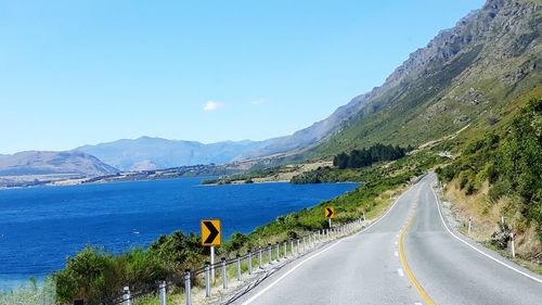 Road by mountains against sky