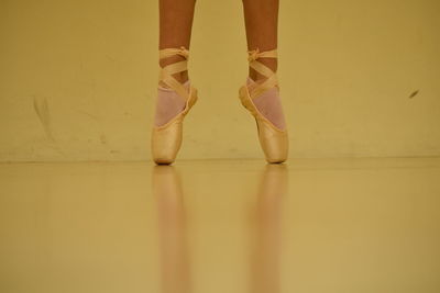 Low section of ballet dancer tiptoeing on floor