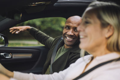 Happy bald man looking at woman driving car