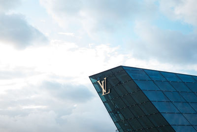 Low angle view of modern building against cloudy sky