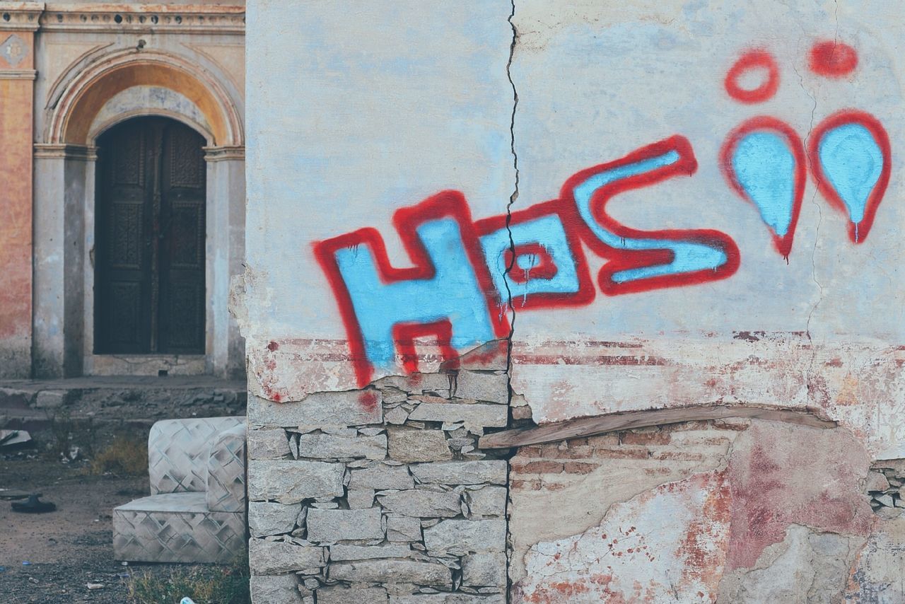 architecture, built structure, building exterior, wall - building feature, brick wall, wall, old, weathered, graffiti, text, abandoned, damaged, window, western script, deterioration, door, day, red, brick, communication