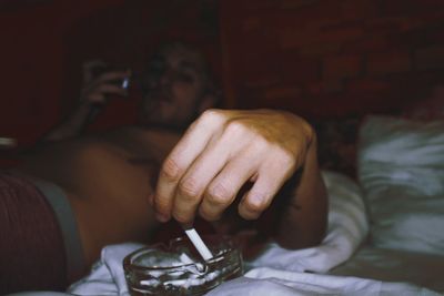 Man smoking cigarette while relaxing on bed