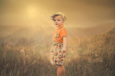 Portrait of happy girl standing on field against sky