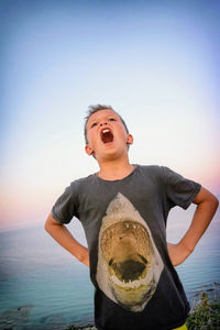 Boy standing by sea against clear sky