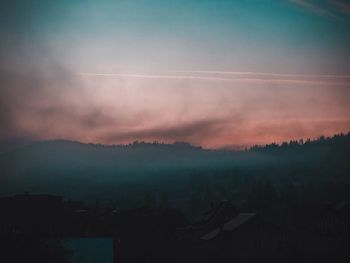 Silhouette of buildings in city during sunset