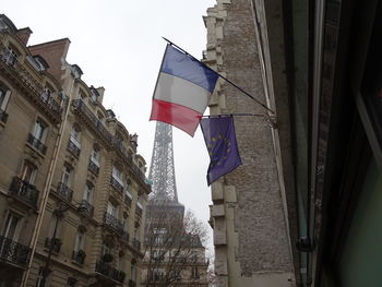 Low angle view of flags in city against sky