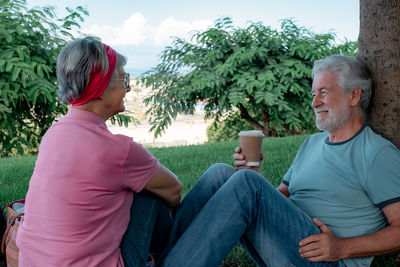 Side view of senior man sitting against trees