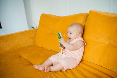 Child on a yellow sofa with flowers at home