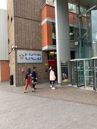 People walking on footpath by buildings in city