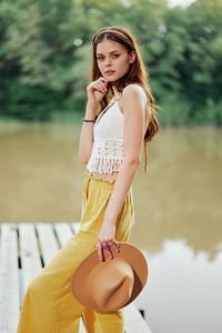 Portrait of young woman standing against trees