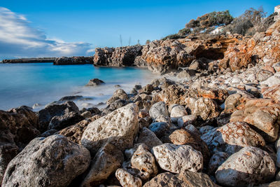 Rocks by sea against sky