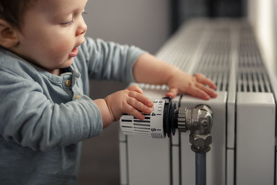 Baby boy playing with thermostat of heater