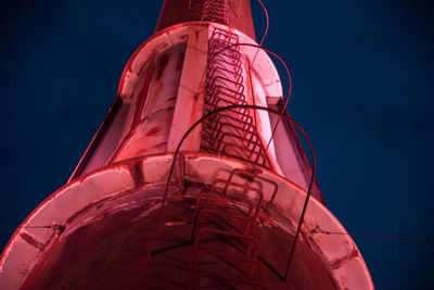 Low angle view of illuminated factory against blue sky