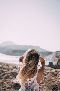 Rear view of woman standing on land against sky