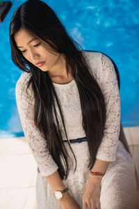 High angle view of beautiful young woman looking away sitting against wall