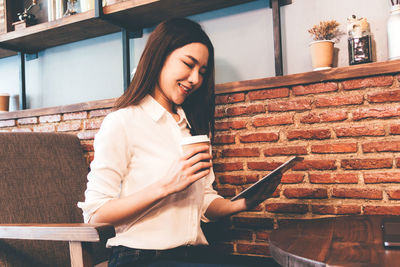 Woman holding coffee cup while reading book in cafe