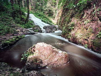 Fallen rocks and rapids in forest. curved mountain stream flowing down on basalt rock.