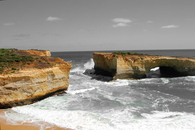 Scenic view of sea by cliff against sky