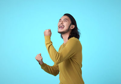 Side view of smiling young woman against blue background
