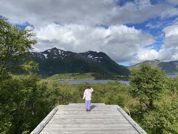 Rear view of woman standing on mountain against sky and mountains 