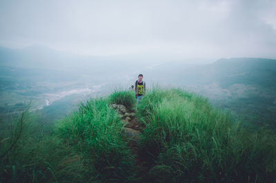 Man walking on mountain against sky