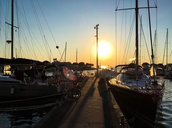 Boats moored at harbor during sunset