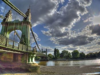 Bridge over river against cloudy sky