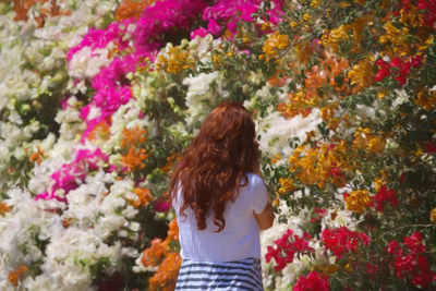 Rear view of woman standing by multi colored flowers