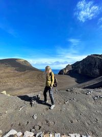 Women standing on rock against blue sky