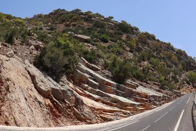 Scenic view of road by mountain against sky