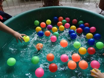 High angle view of children playing with balls floating on water in container