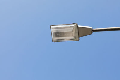 Low angle view of telephone pole against clear blue sky