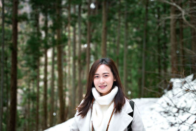 Portrait of young woman against trees in forest