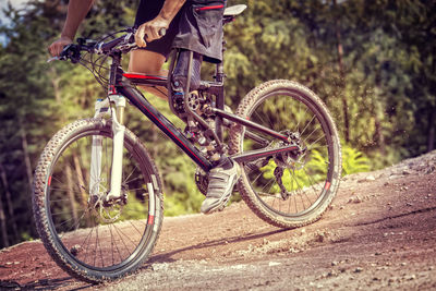 Low section of man with prosthetic leg riding bicycle on field