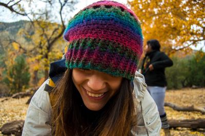 Close-up of smiling woman in knit hat at forest
