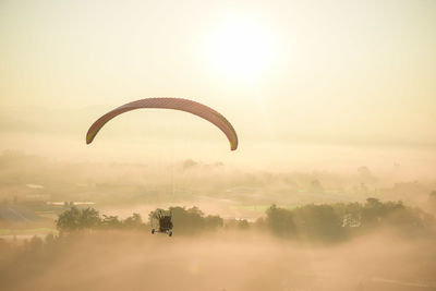 Person paragliding against sky during sunset