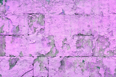 Peeled off old violet paint on flat rough brick wall surface - full frame background and texture