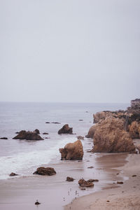 Rocks in sea against clear sky
