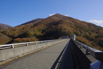 Footbridge over mountain against clear sky