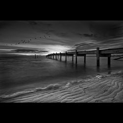 Pier on sea at sunset