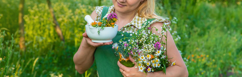 Midsection of young woman holding flower