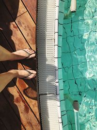 Low section of person standing by swimming pool