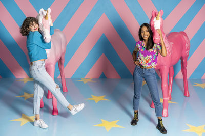 Two happy young women at an indoor theme park with unicorn figures