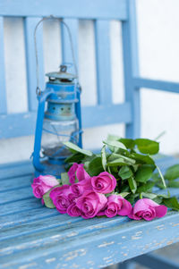 A bouquet of bright pink roses on a blue bench with a blue vintage lamp, march 8