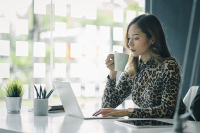 Businesswoman using laptop while sitting in office