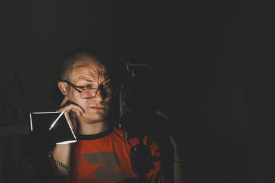 Close-up of photographer with camera in dark studio