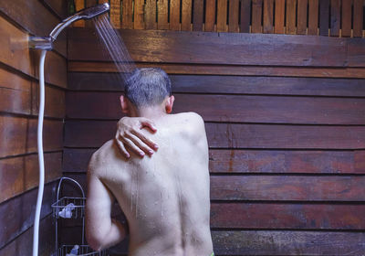 Midsection of shirtless man in bathtub