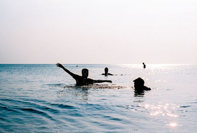 People in sea against clear sky